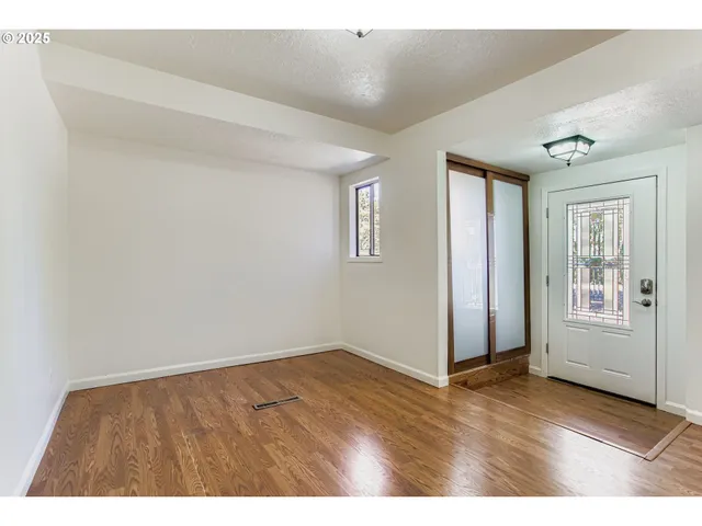 a view of an empty room with window and wooden floor