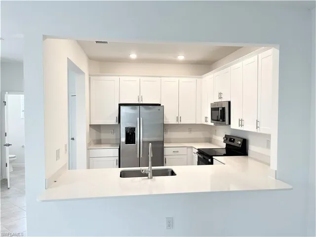 a kitchen with stainless steel appliances a refrigerator sink and white cabinets