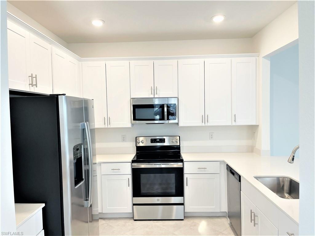 2775 Blossom Way Naples, FL 34120 - Photo 4 of 16 a kitchen with granite countertop white cabinets and stainless steel appliances