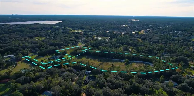 an aerial view of residential house with outdoor space and trees all around