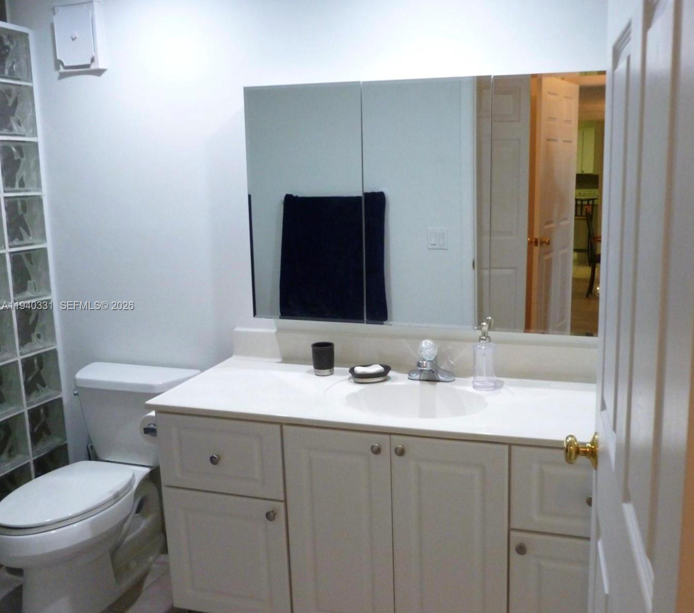 16300 Golf Club Road, Unit 203 Weston, FL 33326 - Photo 8 of 11 a bathroom with a granite countertop toilet sink and mirror