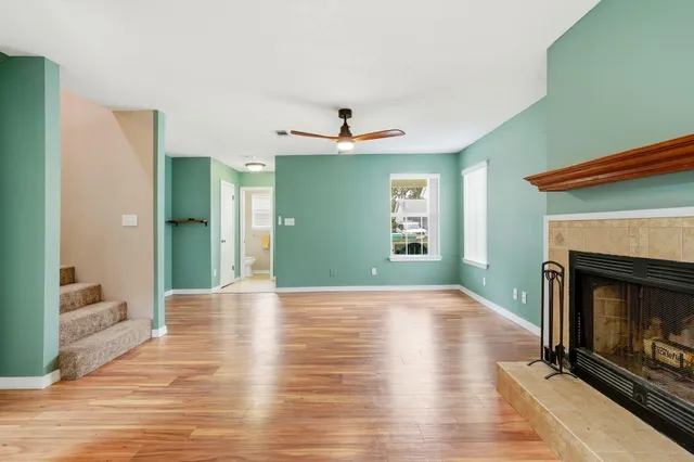 a view of an empty room with wooden floor a fireplace and a window