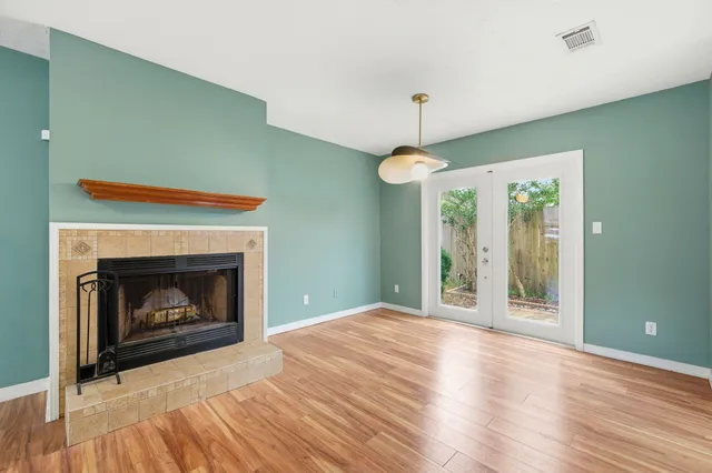a view of an empty room with window and wooden floor