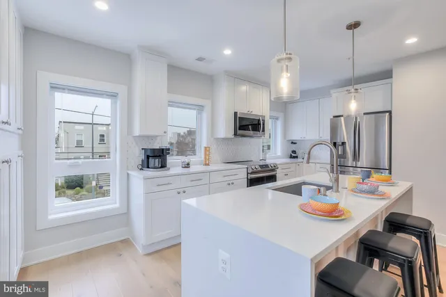 a kitchen with a sink a stove a refrigerator and white cabinets with wooden floor