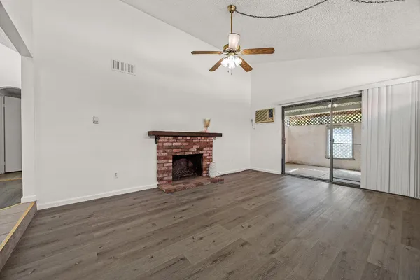 an empty room with wooden floor fireplace and windows