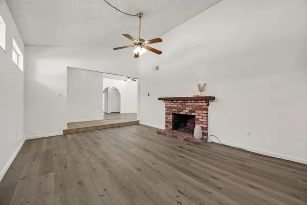 a view of empty room with wooden floor fireplace and fan