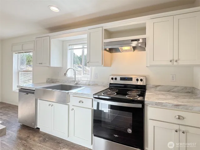 a kitchen with granite countertop stainless steel appliances a stove cabinets and a window