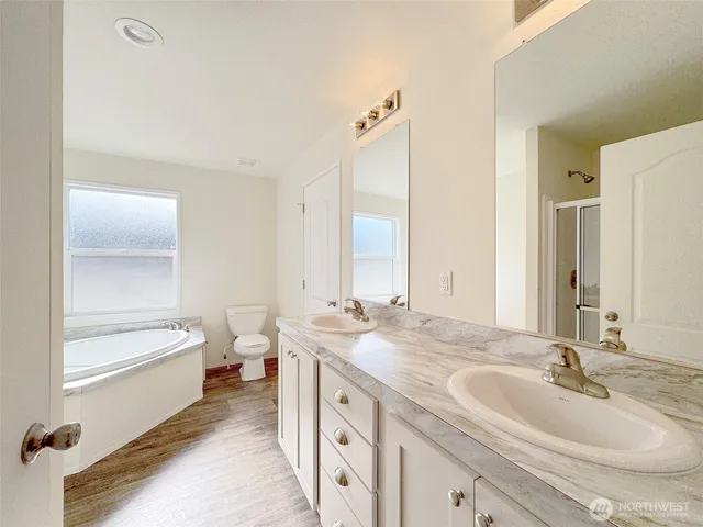 a bathroom with a double vanity sink and mirror with toilet