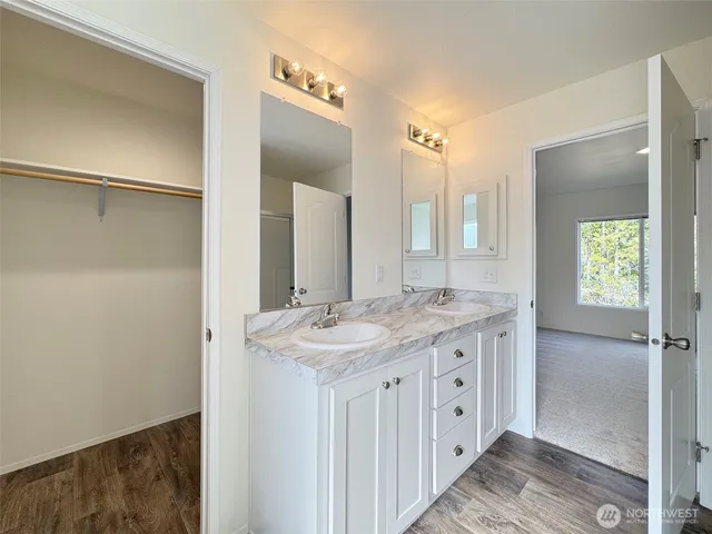 a bathroom with a granite countertop sink two mirror and a shower