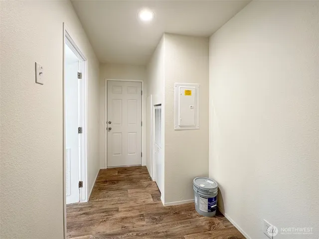 a view of a hallway with wooden floor and a bathroom