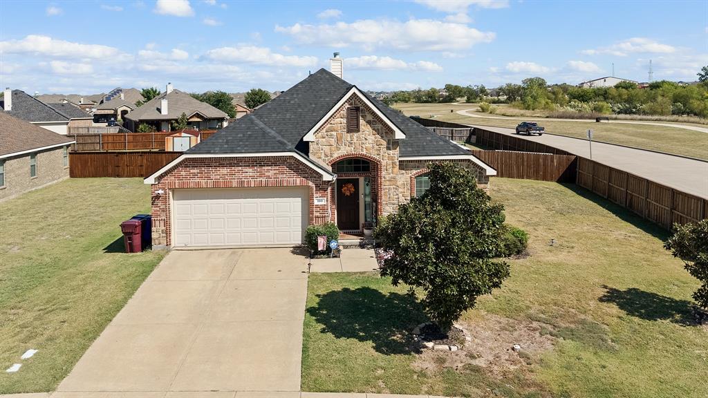 View of front of house with concrete driveway, brick siding, stone siding, an attached garage, and a chimney