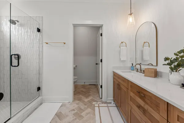 a spacious bathroom with a granite countertop sink a mirror and shower