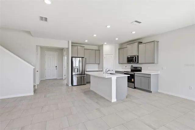 a kitchen with stainless steel appliances granite countertop a refrigerator a stove and a sink