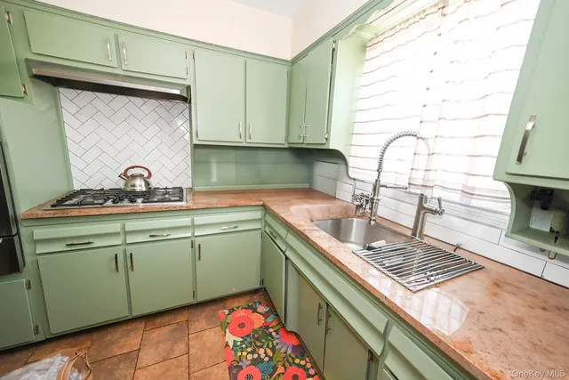 a kitchen with green cabinets a sink and a stove