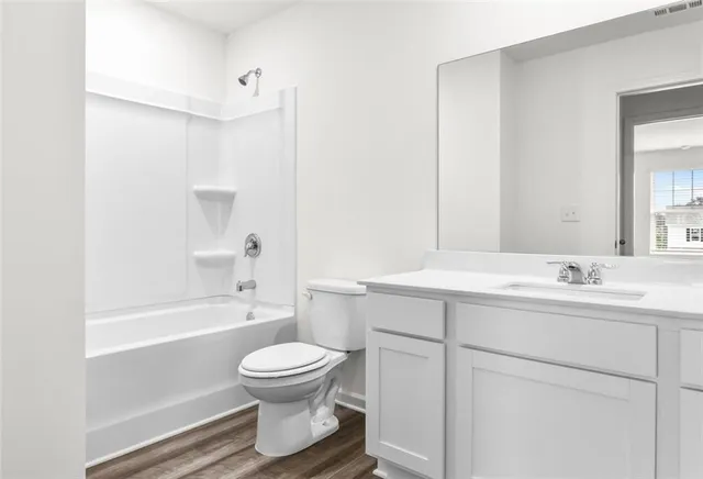 a bathroom with a bathtub shower sink vanity mirror and toilet