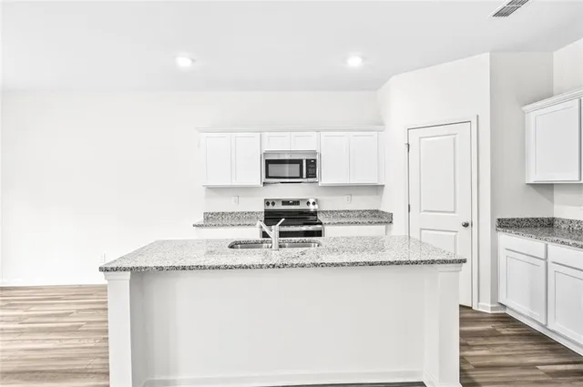 a kitchen with granite countertop a sink stove and refrigerator