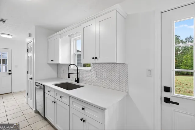 a kitchen with white cabinets and window