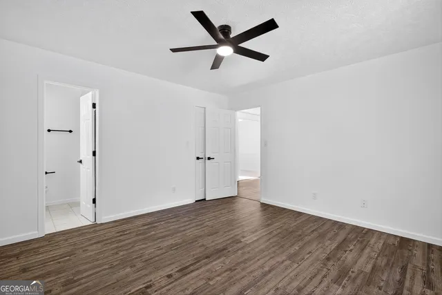 an empty room with wooden floor and ceiling fan