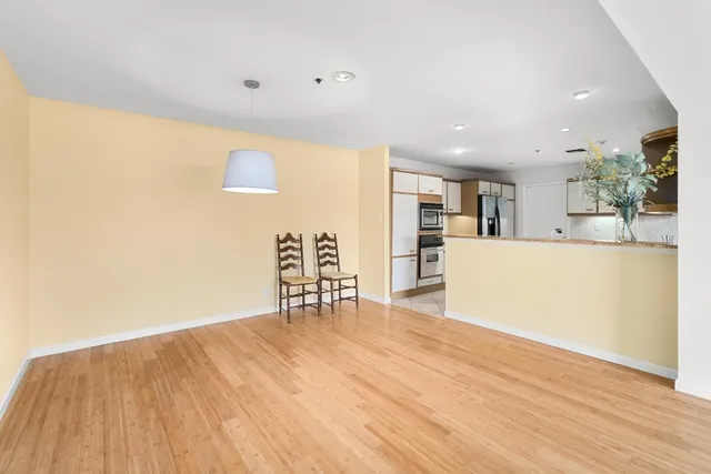 a view of a kitchen with refrigerator and wooden floor