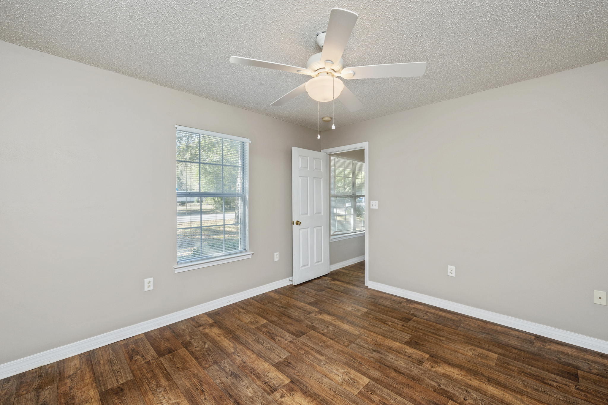 6235 Winstead Road Crestview, FL 32539 - Photo 13 of 31 an empty room with wooden floor fan and windows