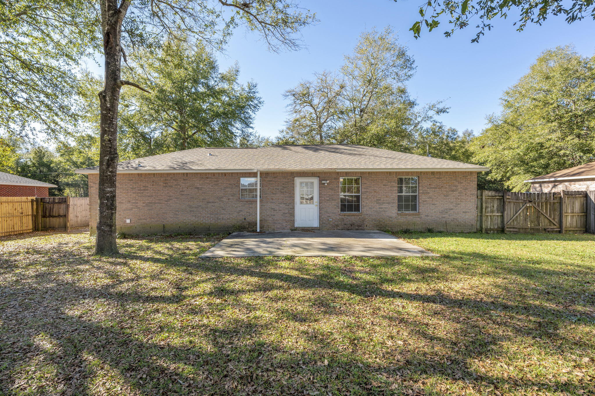 6235 Winstead Road Crestview, FL 32539 - Photo 27 of 31 a backyard of a house with large trees and wooden fence