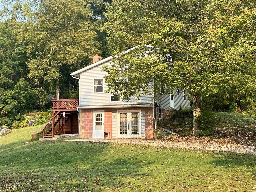 68477 Geese Road Cambridge, OH 43725 - Photo 15 of 32 Side view of house with a yard, a deck, stairway, a forest view, and a chimney