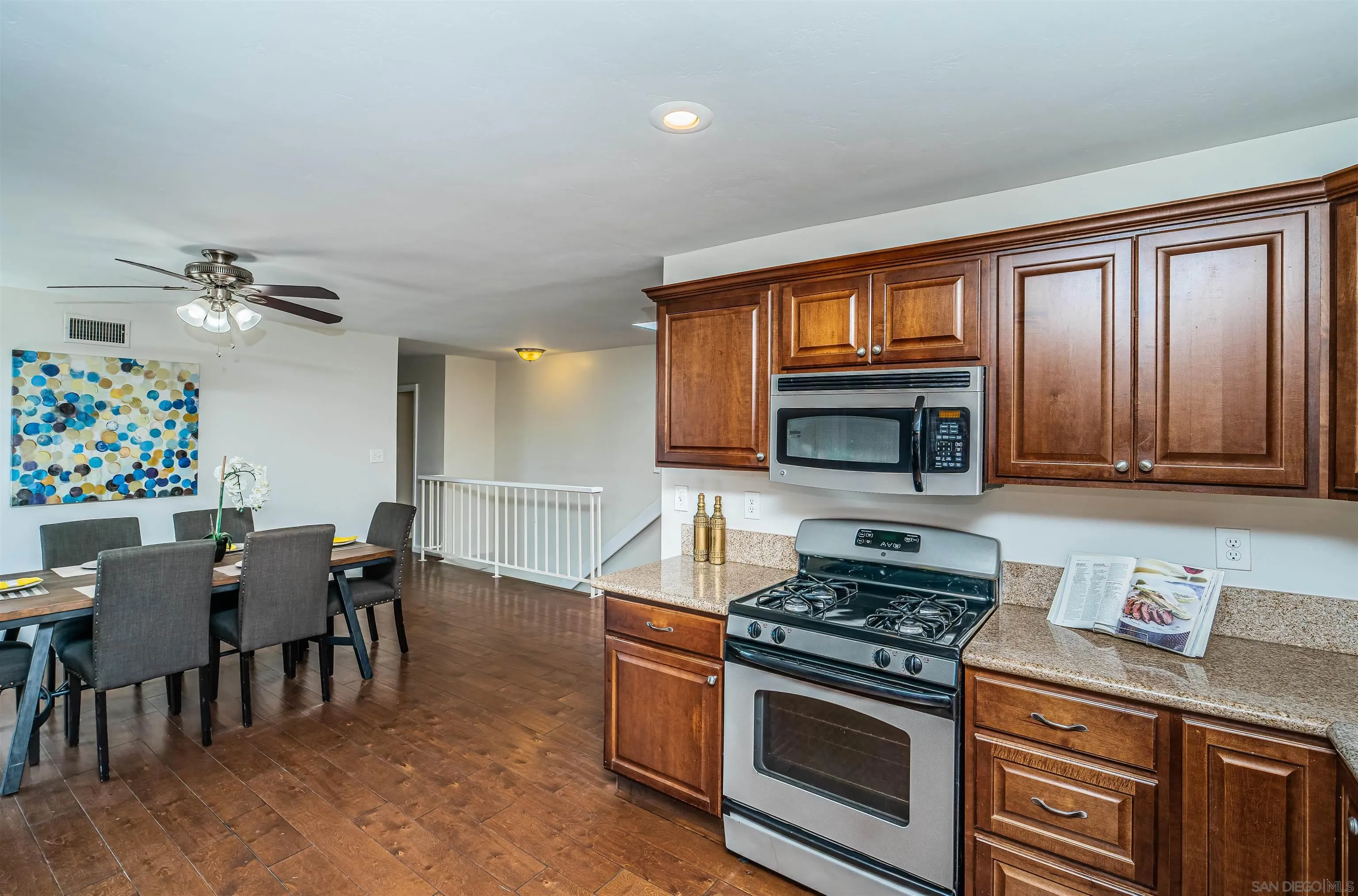 8410 Roy Street Lemon Grove, CA 91945 - Photo 16 of 40 a kitchen with stainless steel appliances granite countertop a stove top oven a sink dishwasher a dining table and chairs with wooden floor