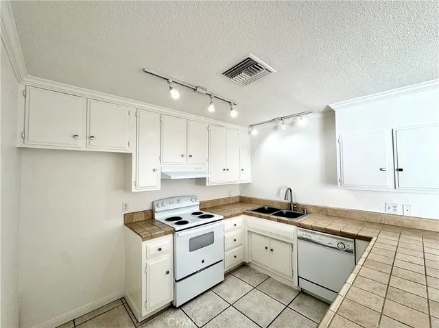 a kitchen with granite countertop white cabinets and white appliances