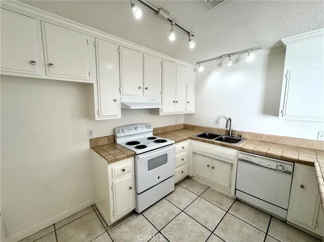 a kitchen with granite countertop white cabinets and white appliances