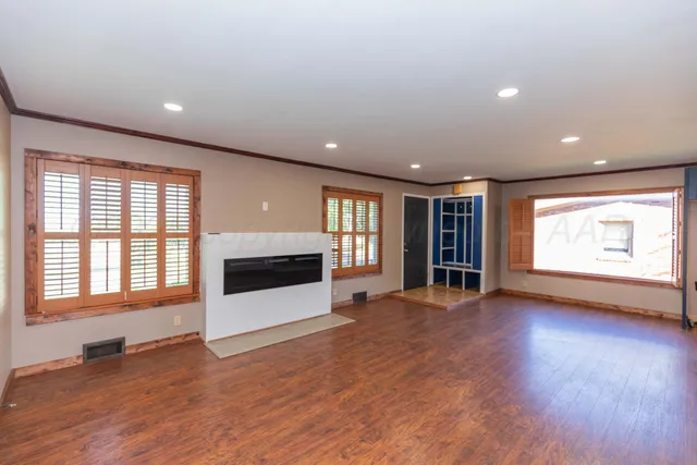 a view of an empty room with a window and wooden floor