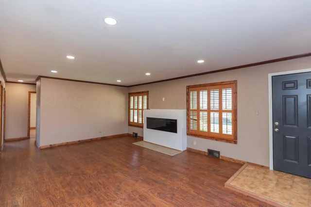 an empty room with wooden floor fireplace and windows