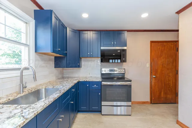 a kitchen with granite countertop wooden cabinets and stainless steel appliances