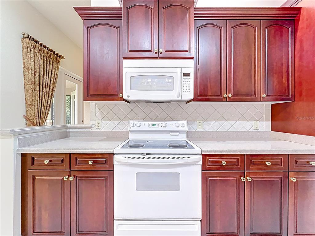 503 Camino Real, Unit 503 Howey-in-the-Hills, FL 34737 - Photo 21 of 65 a stove top oven sitting inside of a kitchen with granite countertop wooden cabinets