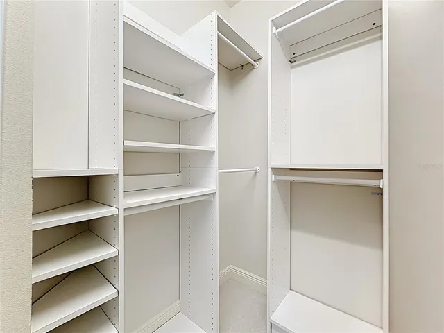 an empty room with a chandelier fan and windows