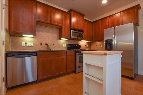 a kitchen with kitchen island granite countertop a sink cabinets and stainless steel appliances