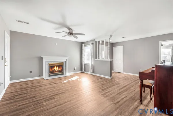 an empty room with wooden floor fireplace and windows
