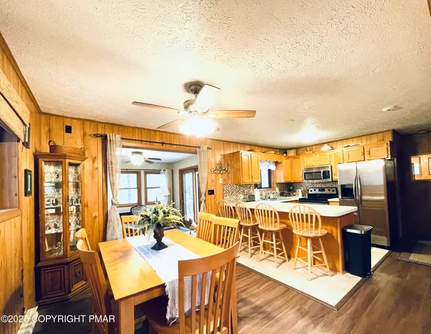 a view of a dining room and livingroom with furniture wooden floor a rug a fireplace and a view