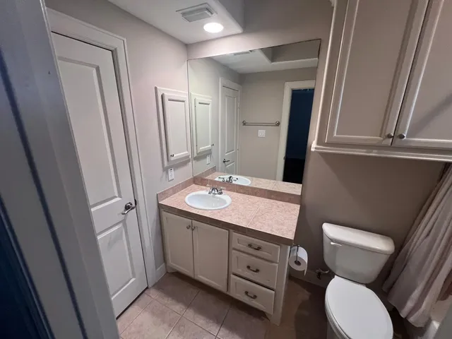 a bathroom with a granite countertop toilet sink and mirror