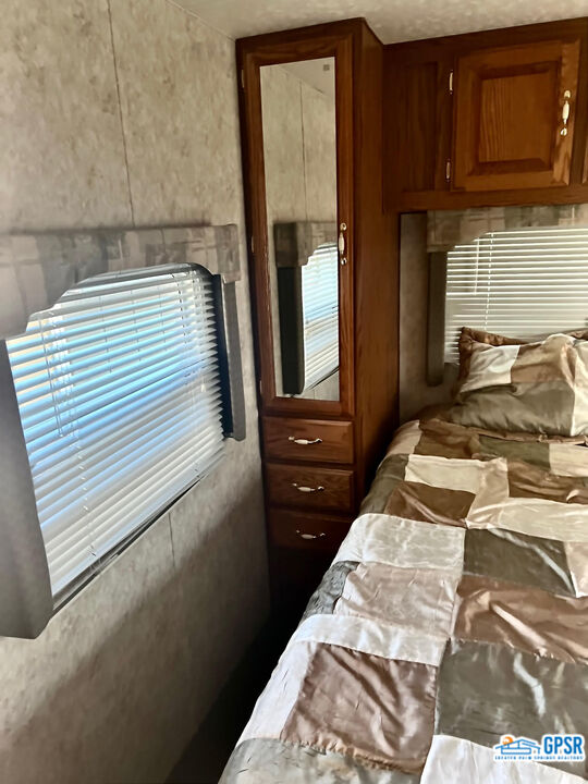 70201 Aurora Road Desert Hot Springs, CA 92241 - Photo 16 of 18 a bedroom with a bed and wooden cabinets