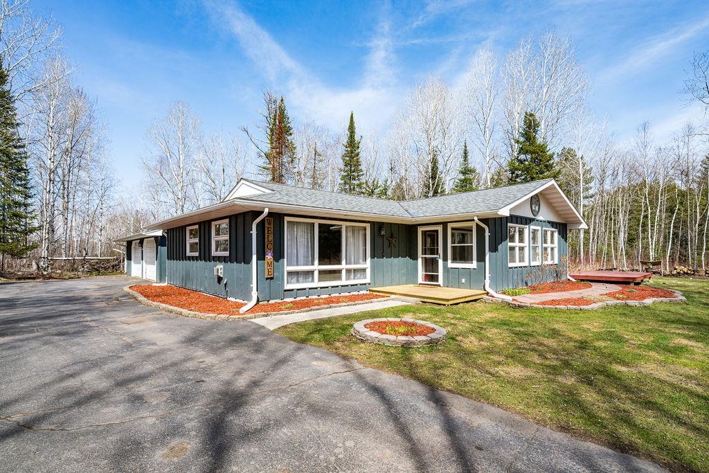 3863 Karky Road Superior, WI 54880 - Photo 2 of 33 View of front facade featuring board and batten siding, a garage, asphalt driveway, and a front lawn