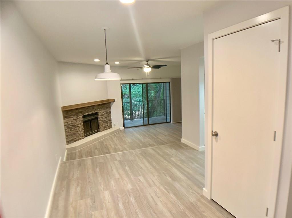 1135 Barton Hills Drive, Unit 252 Austin, TX 78704 - Photo 1 of 19 Unfurnished living room with light wood-style flooring, a ceiling fan, recessed lighting, and a stone fireplace