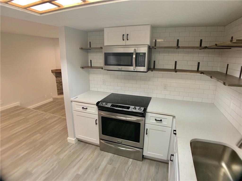 1135 Barton Hills Drive, Unit 252 Austin, TX 78704 - Photo 2 of 19 Kitchen featuring open shelves, white cabinets, stainless steel appliances, light countertops, and light wood finished floors