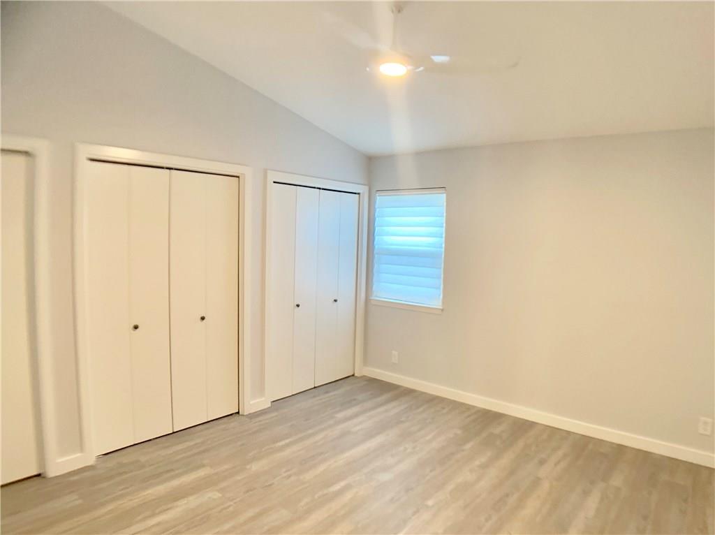 1135 Barton Hills Drive, Unit 252 Austin, TX 78704 - Photo 9 of 19 Unfurnished bedroom featuring two closets, light wood-style flooring, and vaulted ceiling