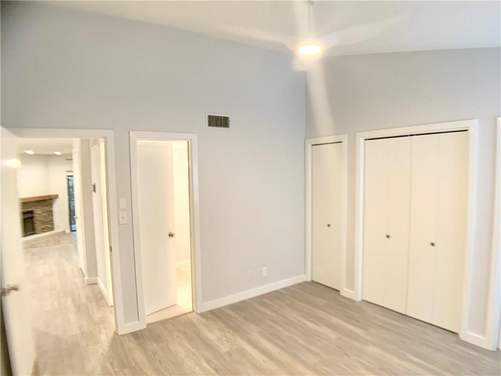 1135 Barton Hills Drive, Unit 252 Austin, TX 78704 - Photo 10 of 19 Unfurnished bedroom featuring two closets, a high ceiling, light wood finished floors, and a fireplace