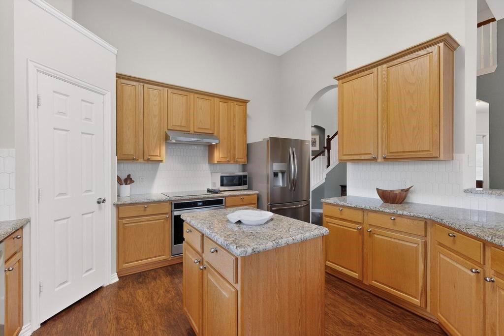 236 Hope Circle Murphy, TX 75094 - Photo 13 of 38 Kitchen featuring updated backsplash, light granite stone counters, stainless steel appliances and cooktop can be switched for gas
