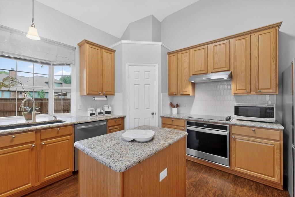 236 Hope Circle Murphy, TX 75094 - Photo 14 of 38 Kitchen with stainless steel appliances, light stone countertops, a center island, walk in pantry and vaulted ceiling