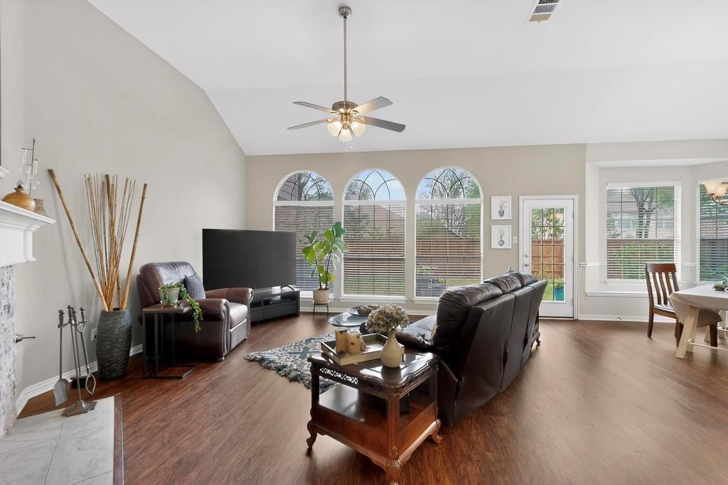 236 Hope Circle Murphy, TX 75094 - Photo 9 of 38 Living area with walls of windows, ceiling fan, lofted ceiling, and a stone fireplace