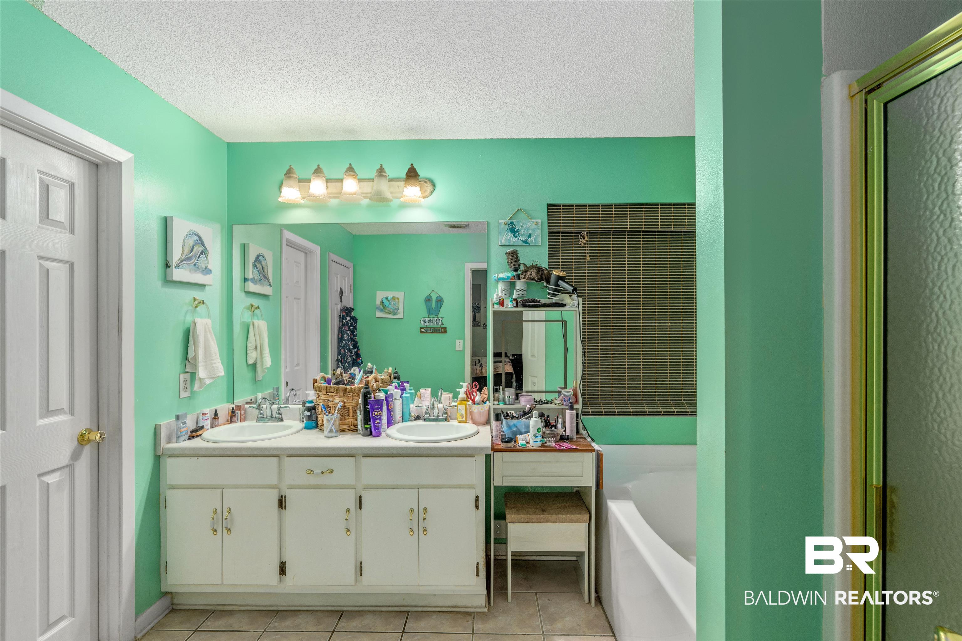 23186 Pecan Street Robertsdale, AL 36567 - Photo 12 of 36 Bathroom featuring a textured ceiling, light tile patterned floors, double vanity, and a bath