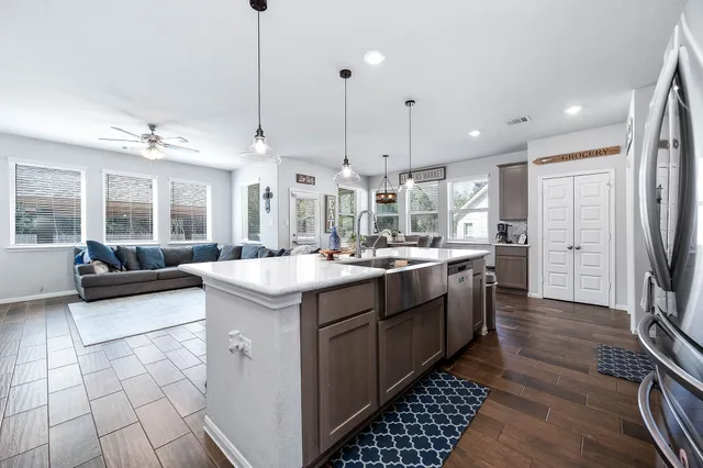 a kitchen with stainless steel appliances kitchen island granite countertop a sink and a refrigerator