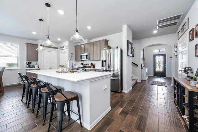 a kitchen with stainless steel appliances a dining table chairs stove and white cabinets